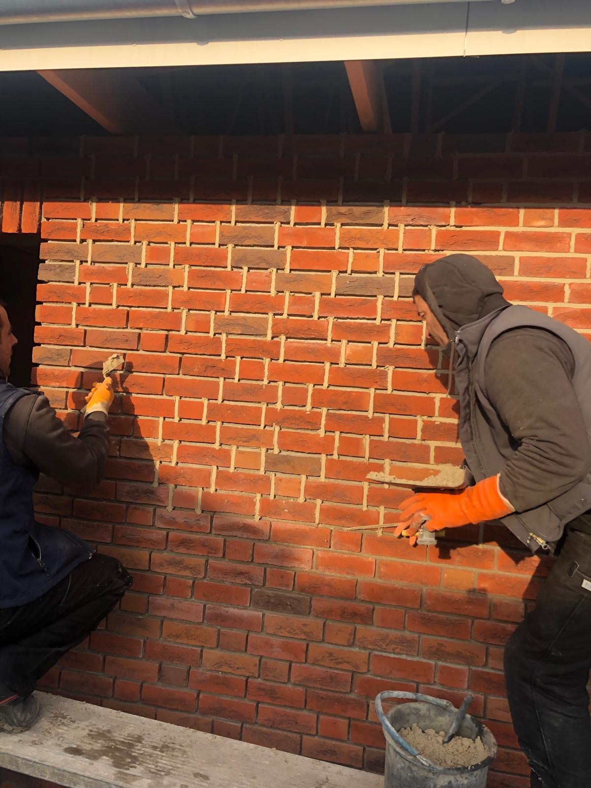 Handwerker beim Verfugen einer Klinkerwand